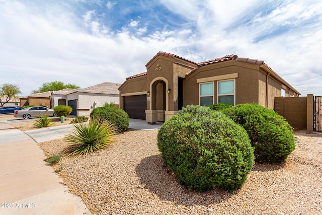 mediterranean / spanish-style home with a tiled roof, stucco siding, a garage, and driveway