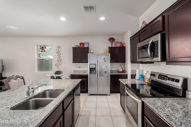 kitchen featuring a sink, light stone countertops, stainless steel appliances, light tile patterned floors, and visible vents