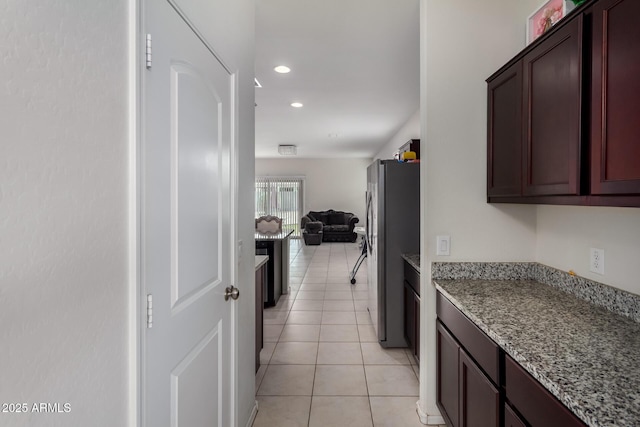 kitchen featuring light stone counters, freestanding refrigerator, open floor plan, light tile patterned floors, and recessed lighting
