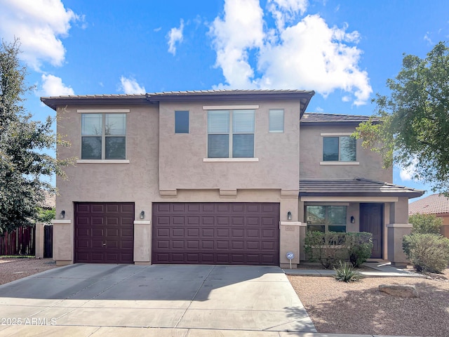 view of front of property featuring a tiled roof, an attached garage, driveway, and stucco siding