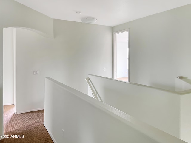 corridor with an upstairs landing, baseboards, and carpet floors