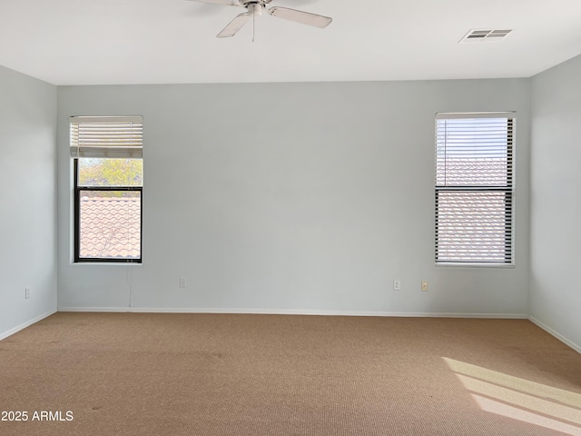 spare room with plenty of natural light, light colored carpet, visible vents, and ceiling fan