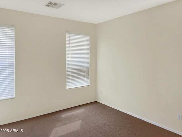 carpeted spare room featuring visible vents and baseboards