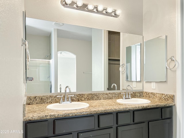 full bath with double vanity, walk in shower, and a sink