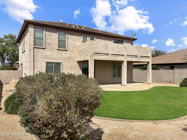 rear view of house featuring a patio, fence, a lawn, and stucco siding