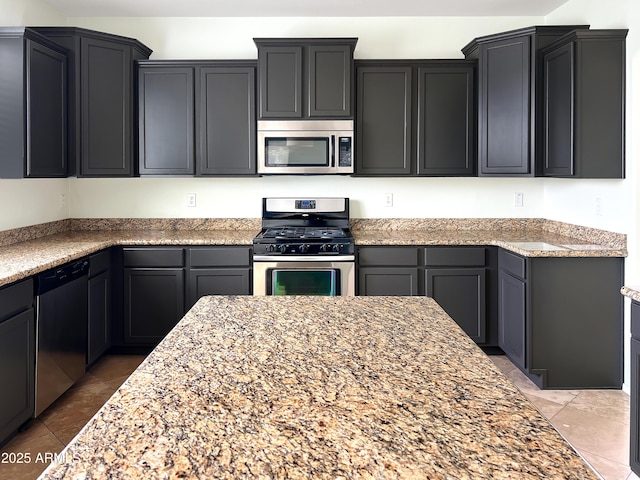 kitchen with light stone counters, light tile patterned floors, and stainless steel appliances