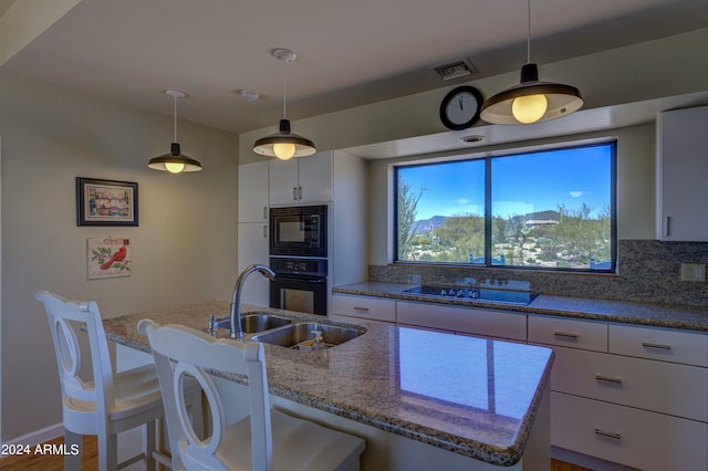 kitchen featuring backsplash, sink, black appliances, and white cabinetry