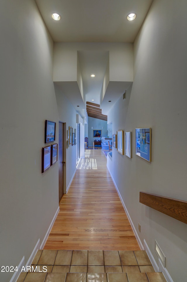 corridor featuring light tile floors and a high ceiling