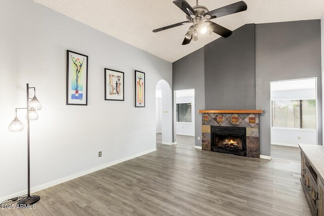 1601 E Cindy St, Chandler, AZ 85225 - unfurnished living room featuring wood finished floors, a fireplace, arched walkways, a ceiling fan, and baseboards