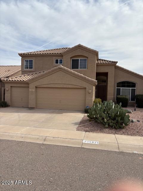 mediterranean / spanish-style home with a tile roof, driveway, an attached garage, and stucco siding