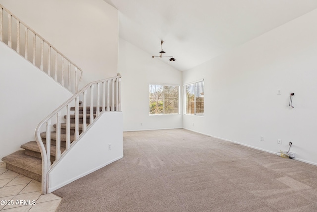 unfurnished living room with light carpet, high vaulted ceiling, stairway, and baseboards