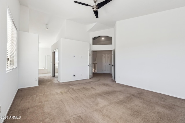 empty room featuring light carpet, baseboards, high vaulted ceiling, and a ceiling fan