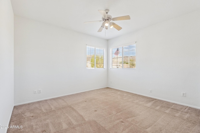 unfurnished room with baseboards, a ceiling fan, and light colored carpet