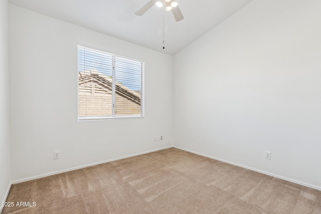 empty room featuring lofted ceiling, light colored carpet, ceiling fan, and baseboards