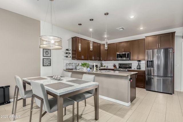 kitchen featuring appliances with stainless steel finishes, tasteful backsplash, dark brown cabinetry, sink, and pendant lighting