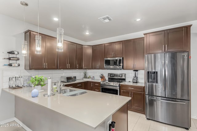 kitchen with dark brown cabinets, stainless steel appliances, sink, pendant lighting, and light tile patterned floors