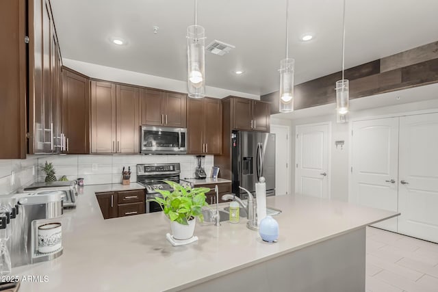 kitchen featuring tasteful backsplash, dark brown cabinets, stainless steel appliances, sink, and hanging light fixtures