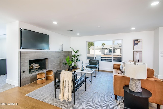 living room with a tile fireplace and light wood-type flooring