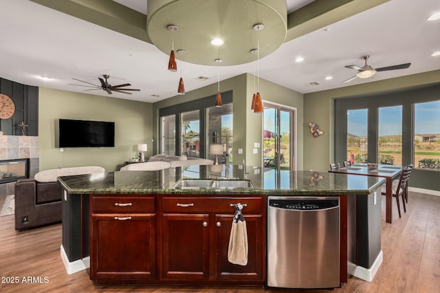 kitchen with light wood-style floors, open floor plan, dark brown cabinets, dark stone counters, and dishwasher