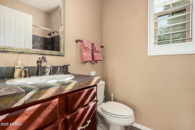 bathroom with toilet, baseboards, and vanity