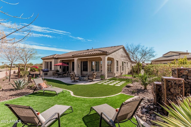 back of property featuring a tiled roof, a yard, a patio area, and stucco siding