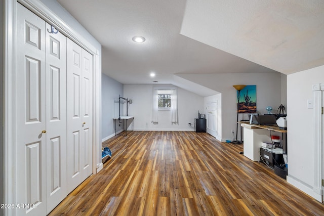 additional living space with a textured ceiling, baseboards, and wood finished floors