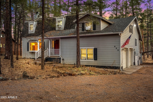 view of front of house featuring driveway, a shingled roof, and a garage