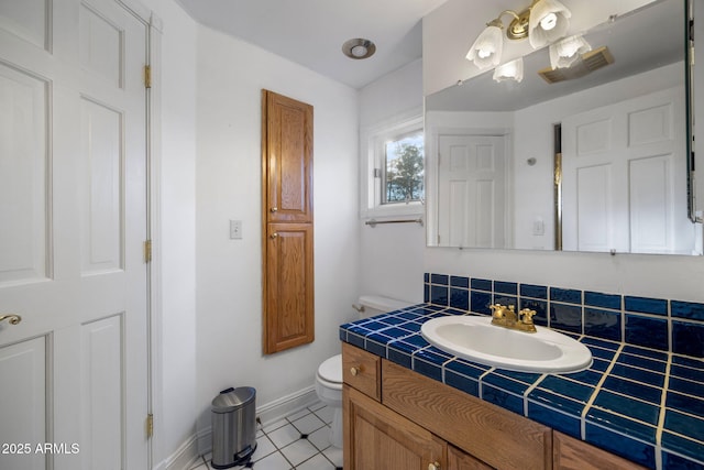 bathroom featuring toilet, visible vents, vanity, baseboards, and tile patterned floors