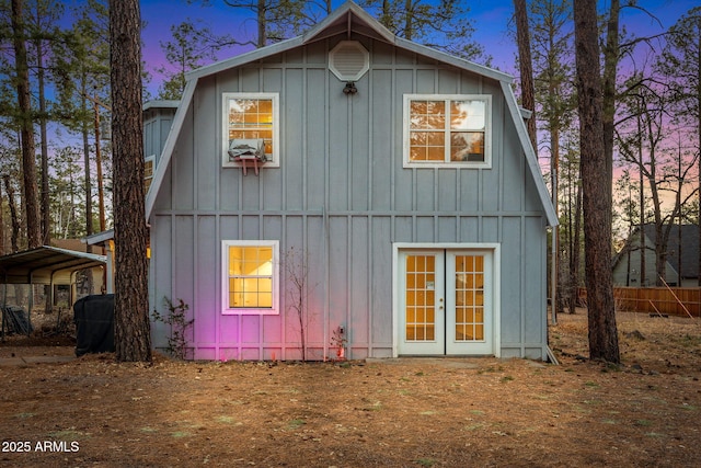 back of house with a detached carport, french doors, board and batten siding, and a gambrel roof