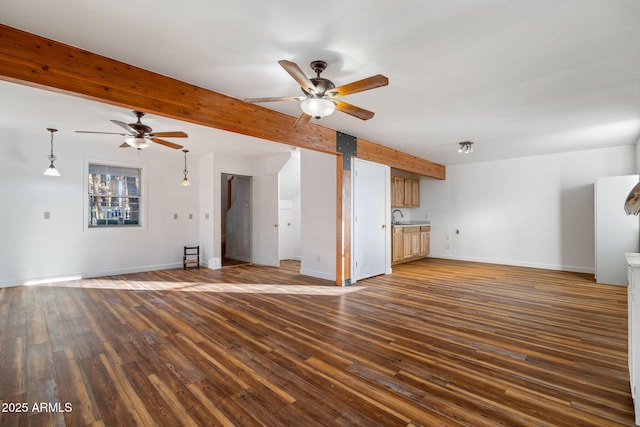 unfurnished living room featuring a ceiling fan, beam ceiling, baseboards, and wood finished floors