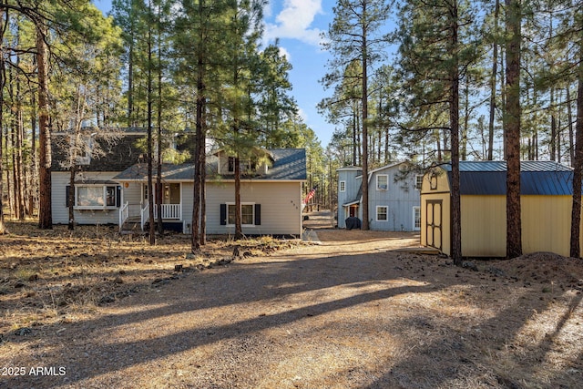 back of property with an outbuilding, a standing seam roof, and metal roof