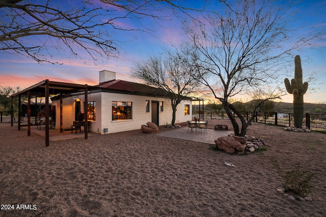 back house at dusk featuring a fire pit and a patio area