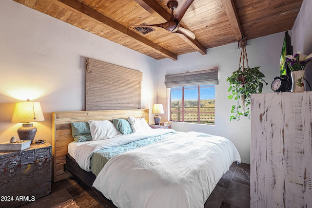 bedroom with ceiling fan, dark tile patterned flooring, beamed ceiling, and wood ceiling