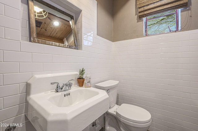 bathroom with tile walls, sink, and toilet