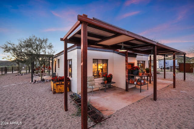 back house at dusk featuring a patio