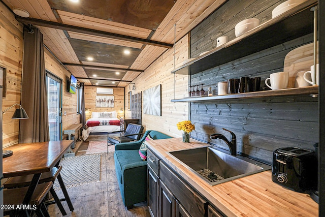 kitchen with wood walls, wood-type flooring, butcher block counters, wooden ceiling, and sink