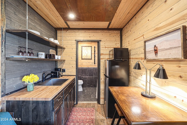 kitchen featuring wood walls, stainless steel refrigerator, sink, wooden ceiling, and wooden counters