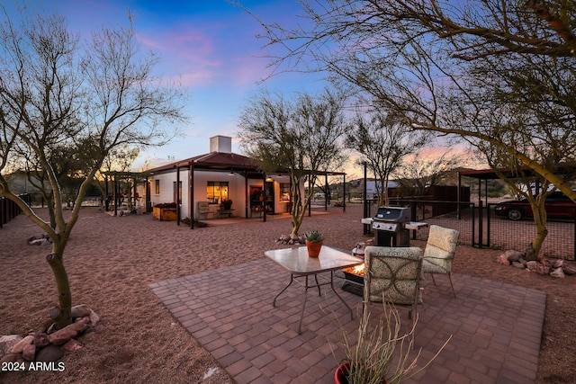 patio terrace at dusk with a fire pit and area for grilling