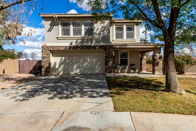 traditional-style house with a garage, brick siding, fence, driveway, and stucco siding