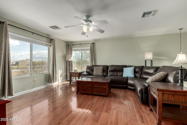 living area featuring ceiling fan, wood-type flooring, visible vents, and baseboards