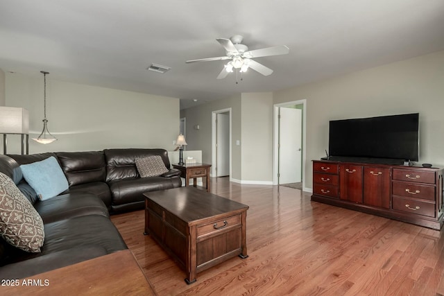 living room featuring light wood-style flooring, visible vents, ceiling fan, and baseboards