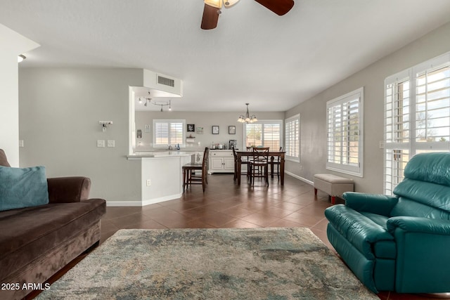 living area with dark tile patterned flooring, visible vents, baseboards, and ceiling fan with notable chandelier