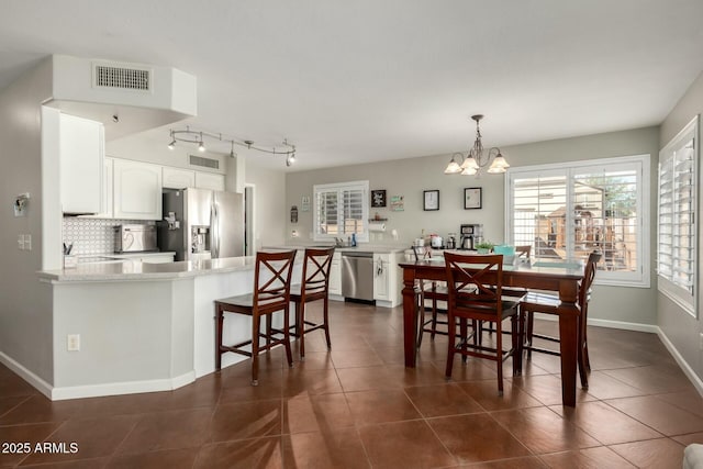 dining area featuring a chandelier, visible vents, dark tile patterned floors, and baseboards