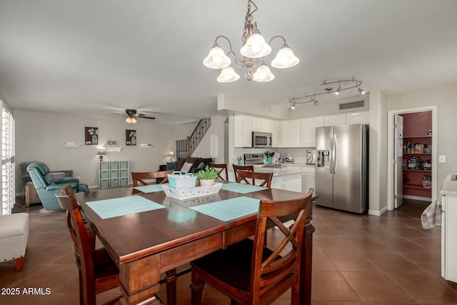 dining area featuring ceiling fan with notable chandelier, visible vents, dark tile patterned floors, and stairs