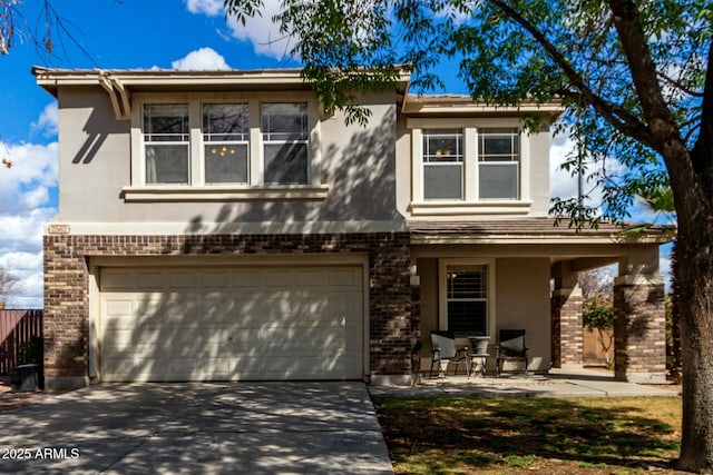 view of front of house featuring a garage, driveway, brick siding, and stucco siding