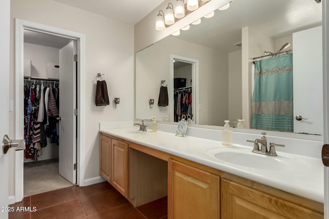 bathroom featuring double vanity, a spacious closet, a sink, and tile patterned floors