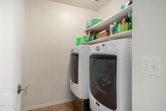 laundry area with laundry area, baseboards, visible vents, wood finished floors, and washer and dryer