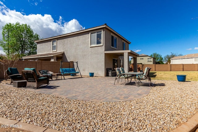 back of house with a fenced backyard, a patio, and stucco siding