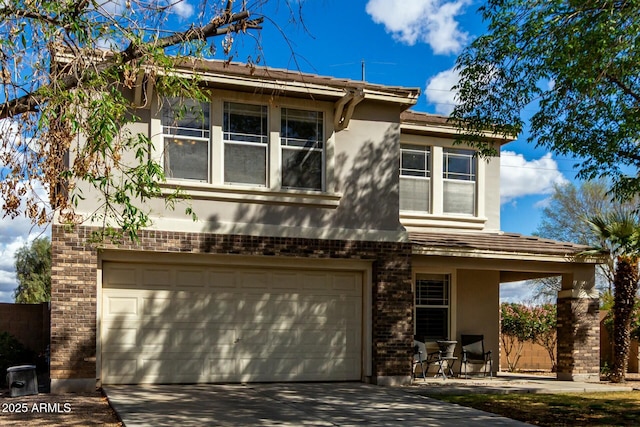 view of front of house featuring driveway, brick siding, an attached garage, and stucco siding