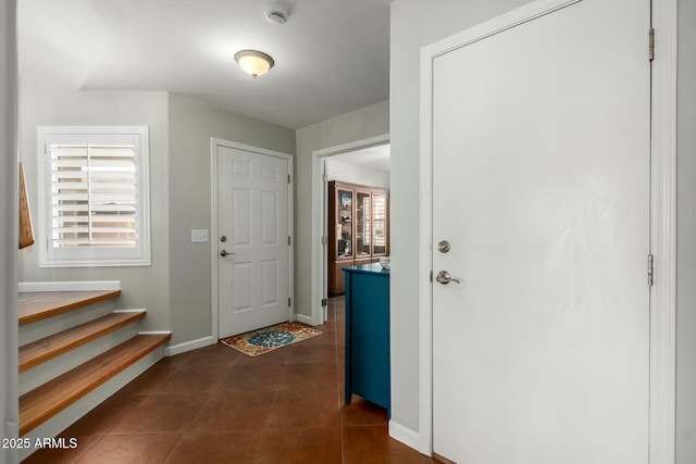 entryway with stairs, baseboards, and dark tile patterned flooring